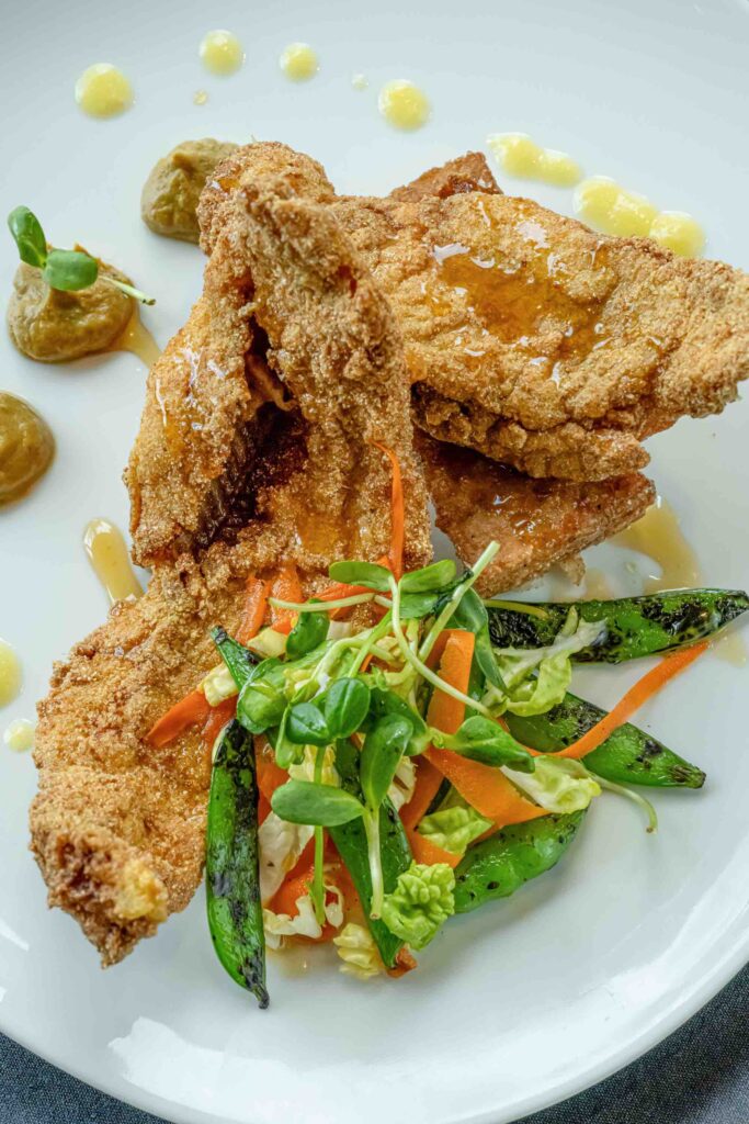 Overhead shot of Balinese catfish plated with colorful garnishes