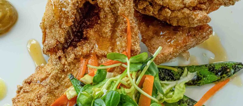 Overhead shot of Balinese catfish plated with colorful garnishes